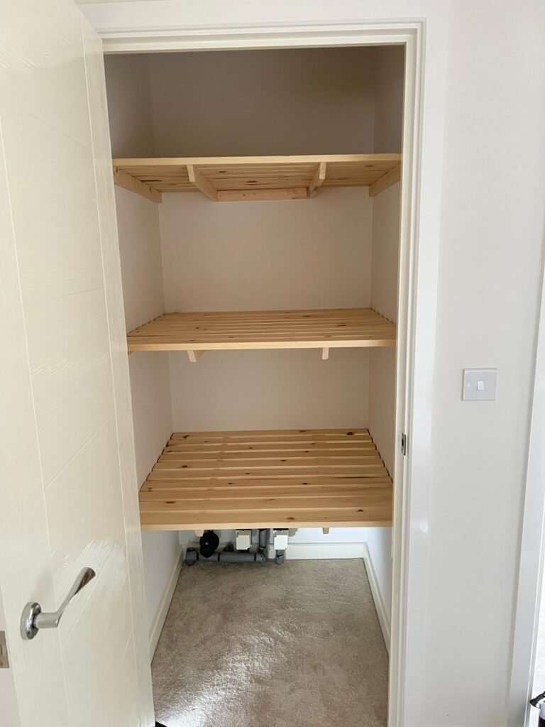 Airing cupboard fitted with three tiers of pine slatted shelving