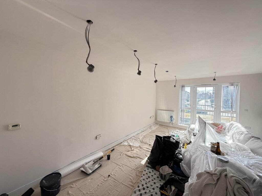 Living room ceiling with cables hanging from holes ready for new spotlights