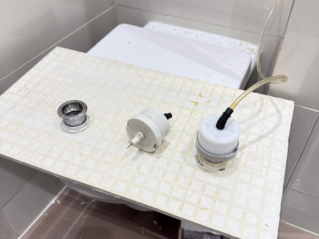 Concealed cistern parts including fill valve and flush button laid out during a toilet repair