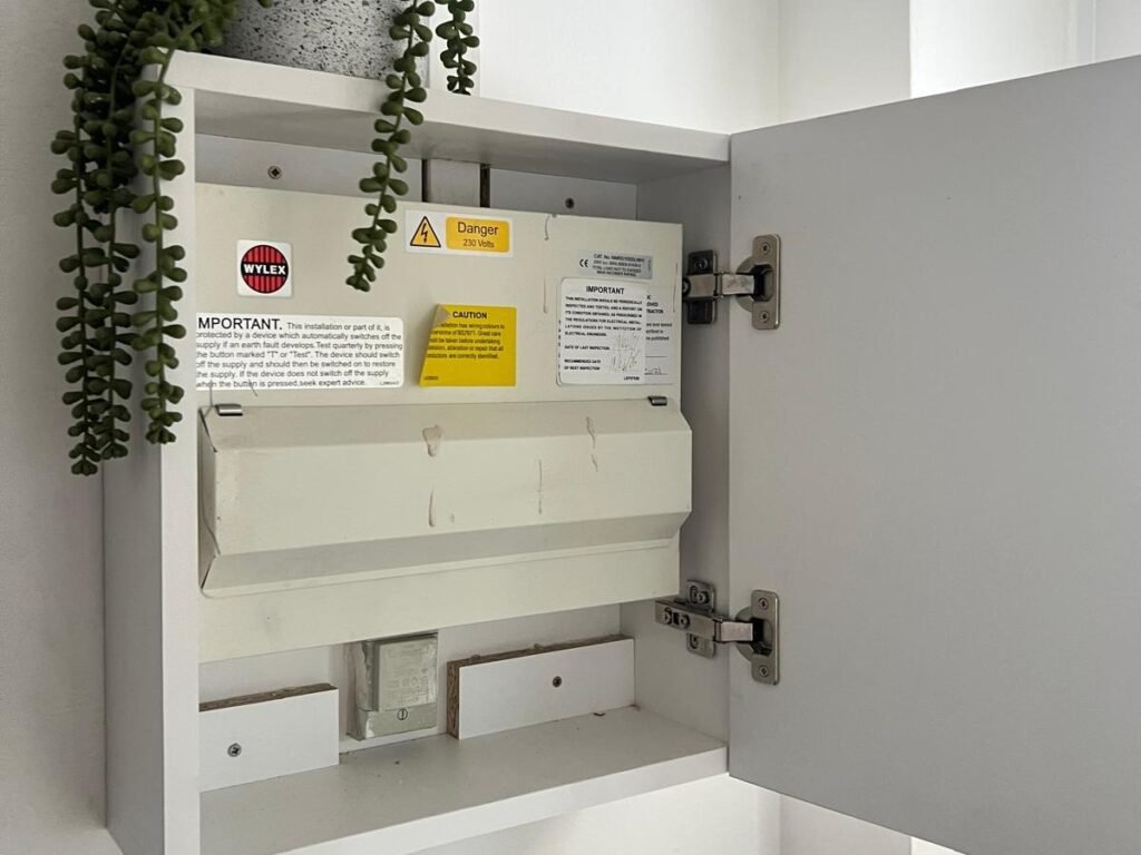 Bespoke white cupboard built around an electrical consumer unit with a soft close door