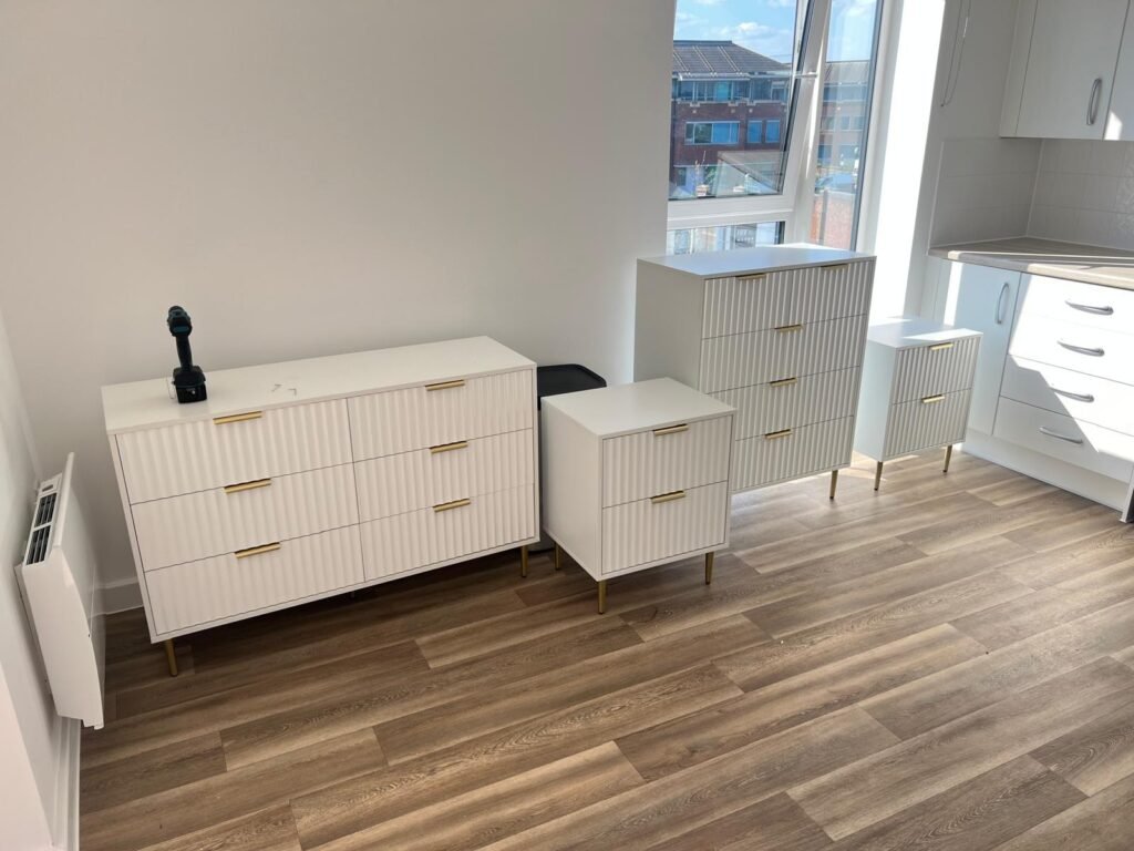 White ribbed chest of drawers, bedside tables and tallboy assembled in a new flat