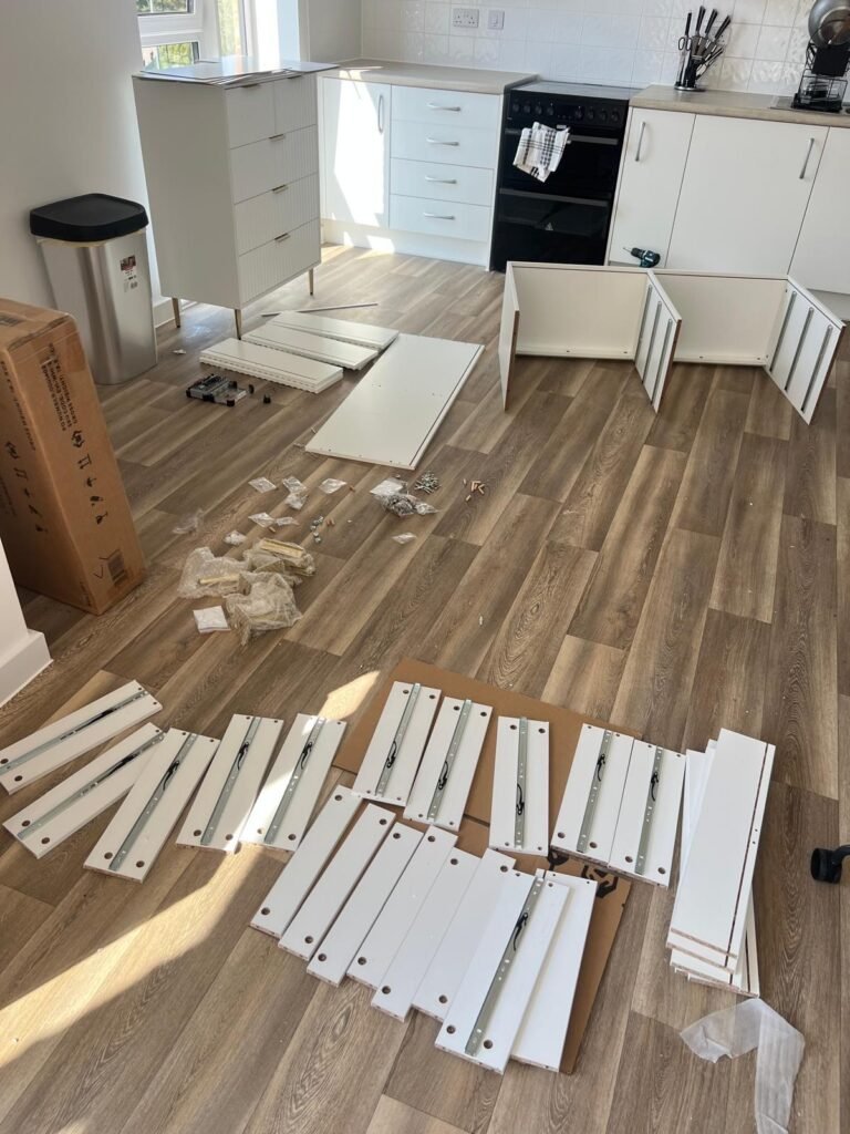 Flat-pack chest of drawers parts laid out on a kitchen floor before assembly