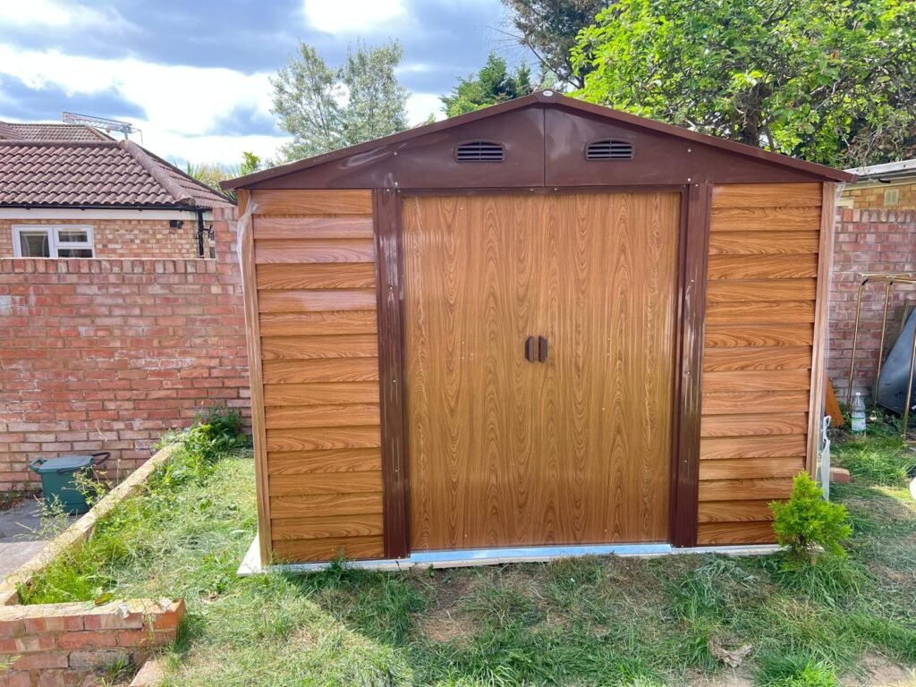 Metal garden shed with wood effect panels assembled at the bottom of a garden in Hounslow