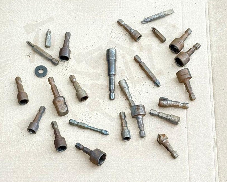Rusty screwdriver and socket driver bits laid out before laser rust removal