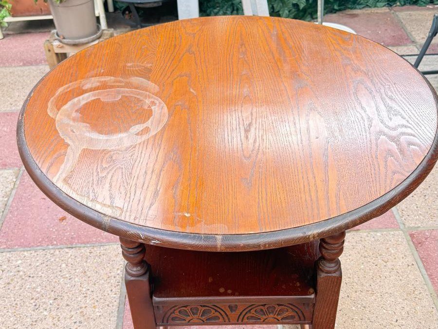 Oak side table with dark varnish and a white water ring stain before laser cleaning